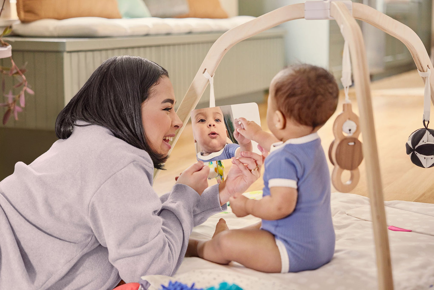 Woman playing with a baby on a mat in a baby gym.