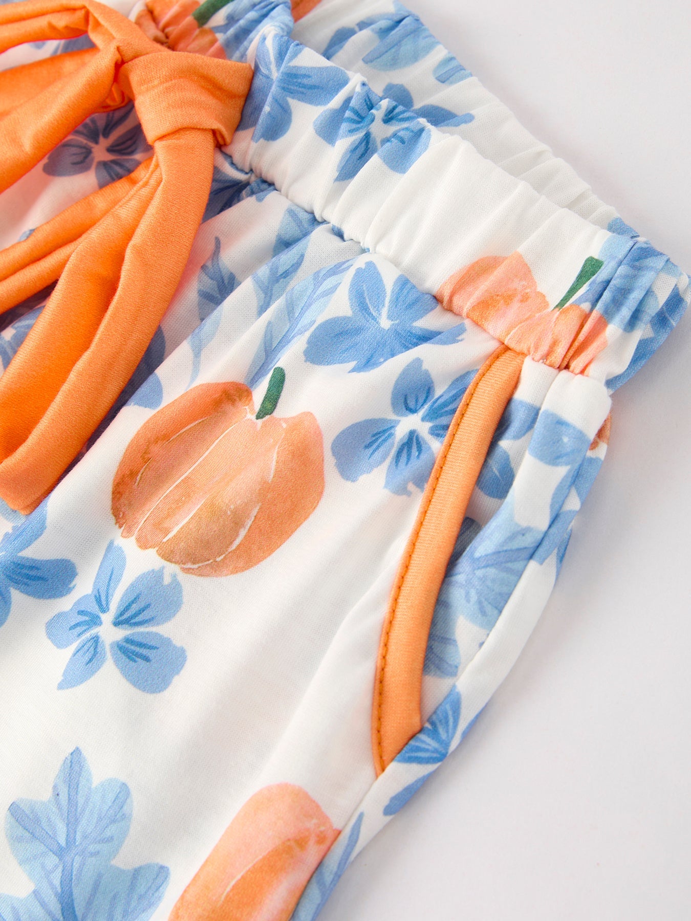 Close-up of a floral pajama set with orange pumpkin accents on a white background