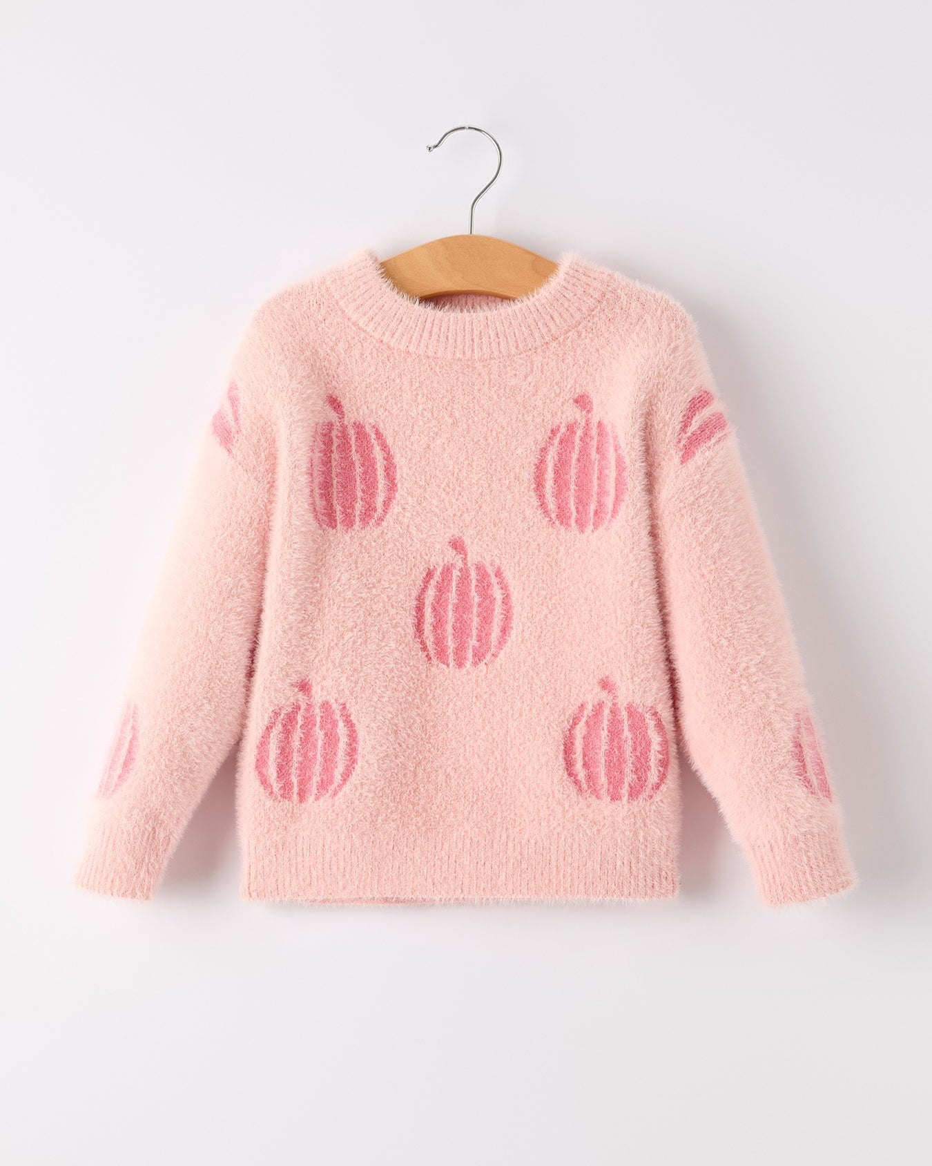 Pink sweater with pumpkin patterns on a hanger against a white background