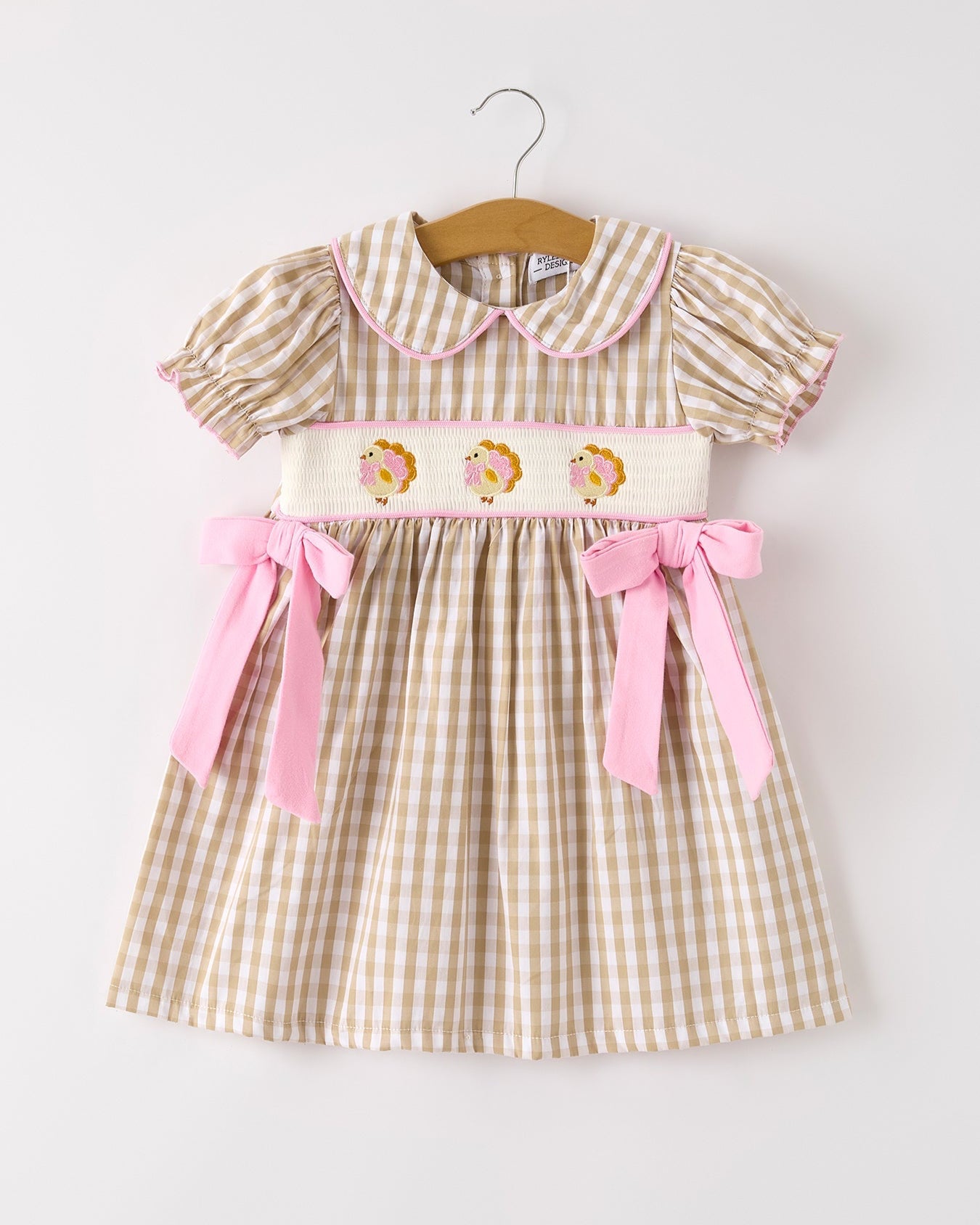 Children's dress with checkered pattern and pink accents on a white background