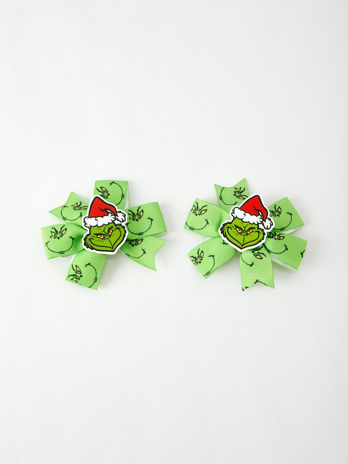 Two green hair bows with Grinch faces on a white background