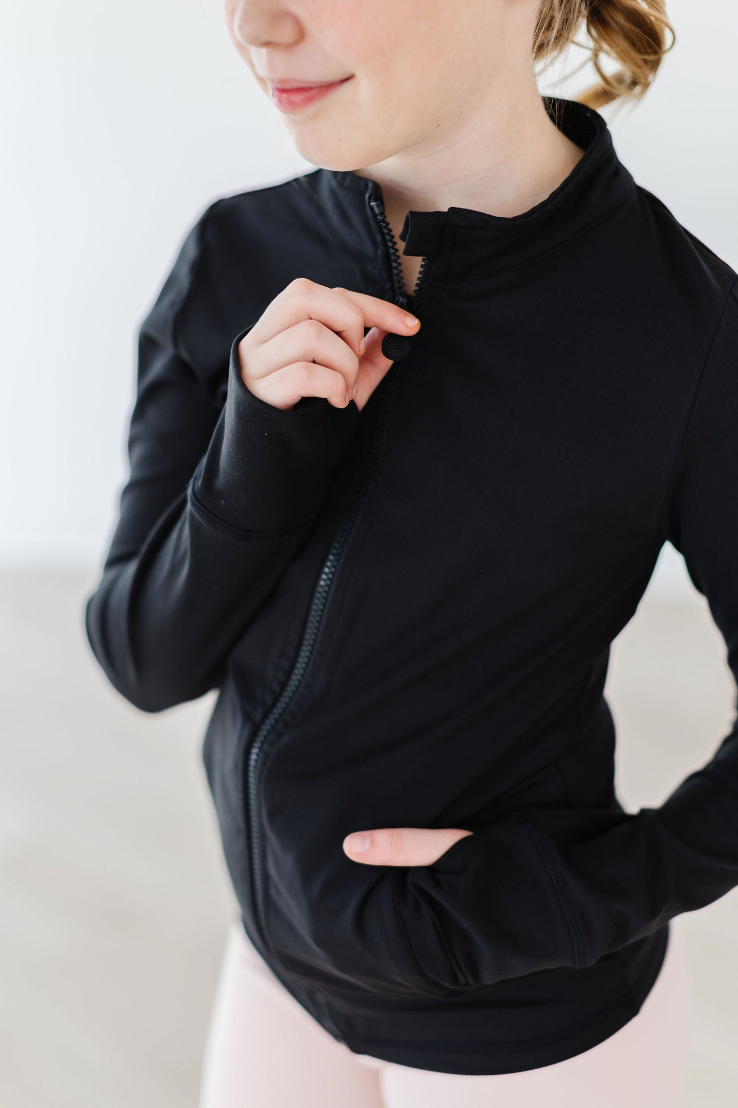 Person wearing a black long-sleeve top with a zipper on a white background