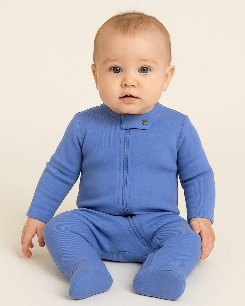 Baby wearing a blue onesie sitting on a beige background