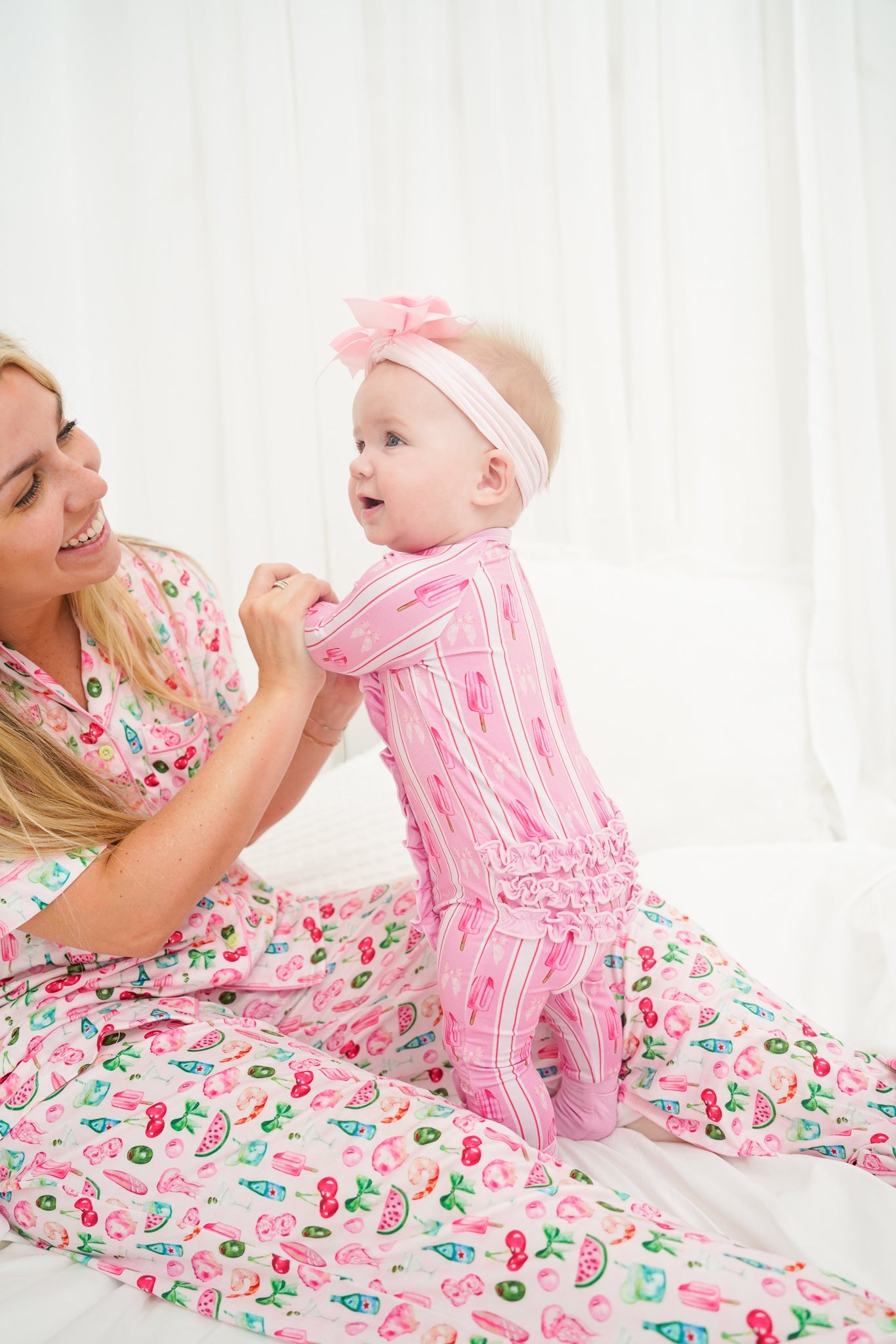 Woman and baby in matching pink outfits with fruit patterns on a white background