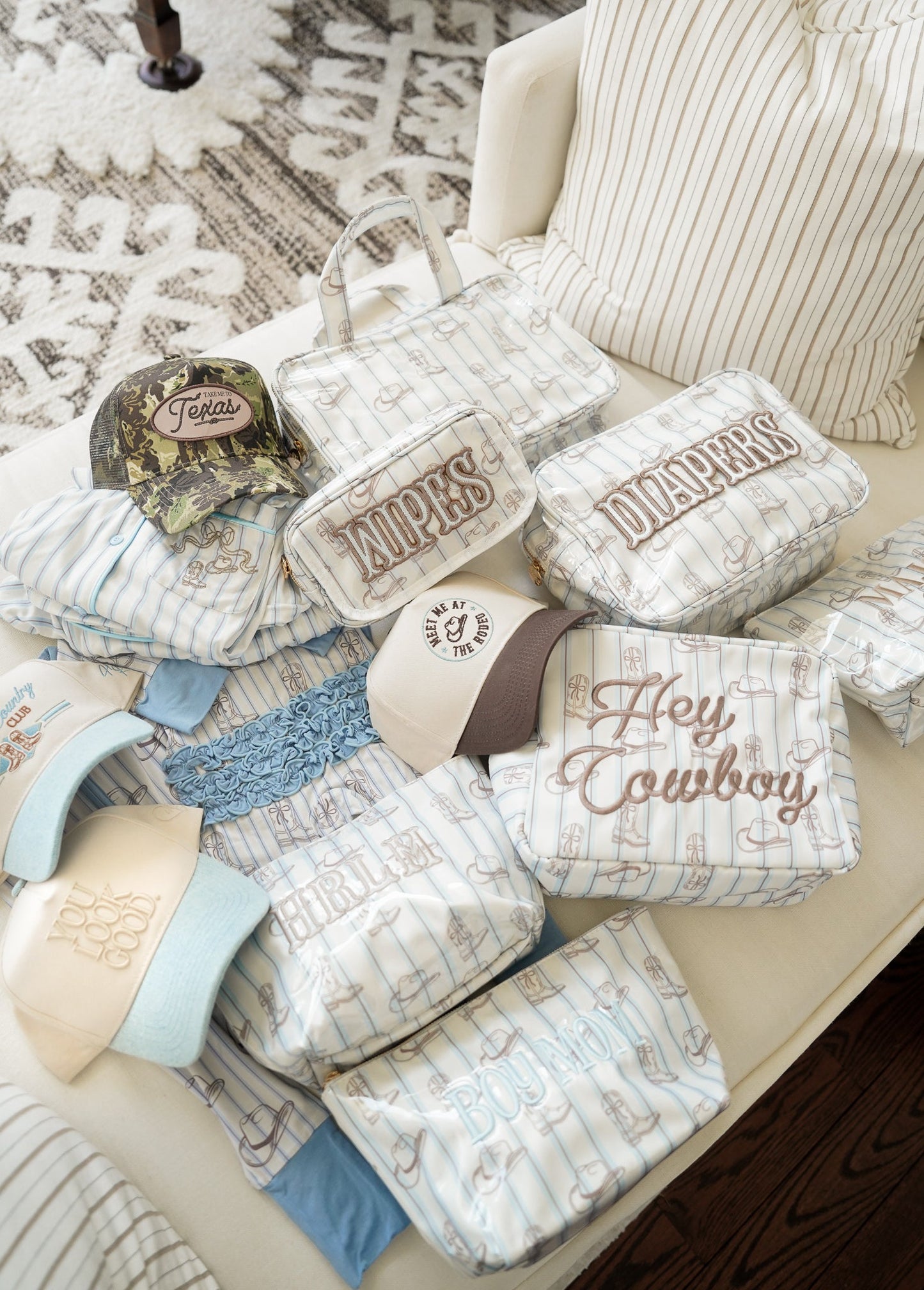 Collection of baby items including hats, blankets, and diaper bags on a couch.