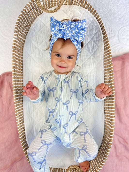 Baby in a crib wearing a blue and white outfit with a matching headband.