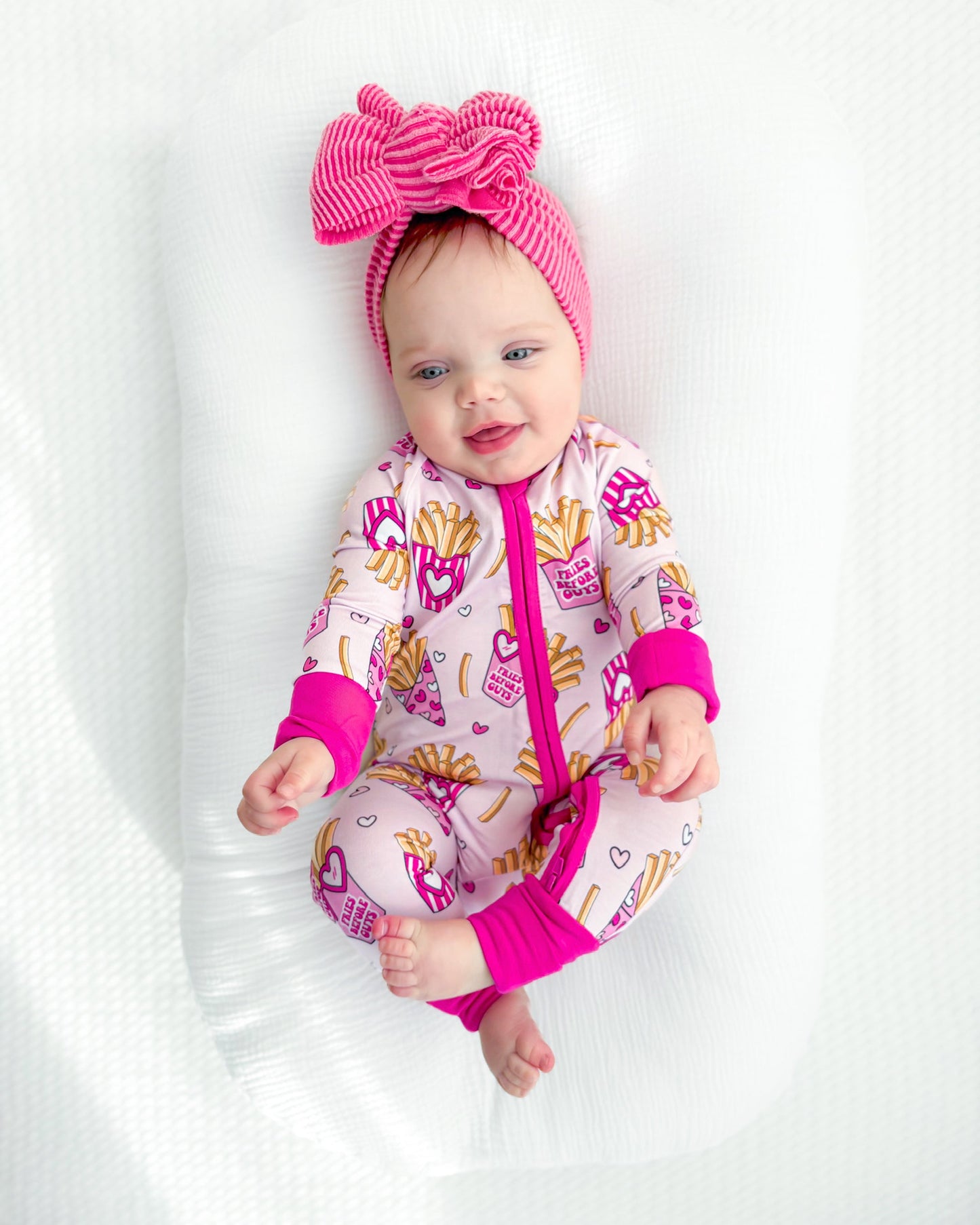 Baby in a pink and white outfit with a large bow on a white background