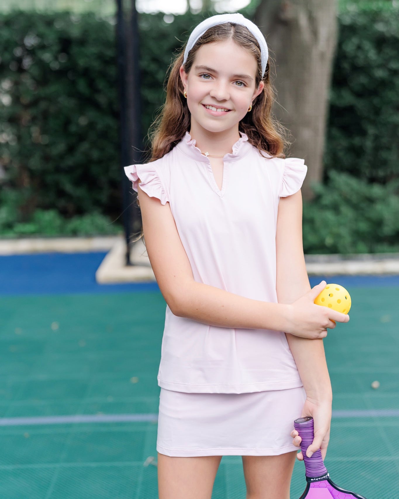 Young girl on a tennis court holding a racket and ball