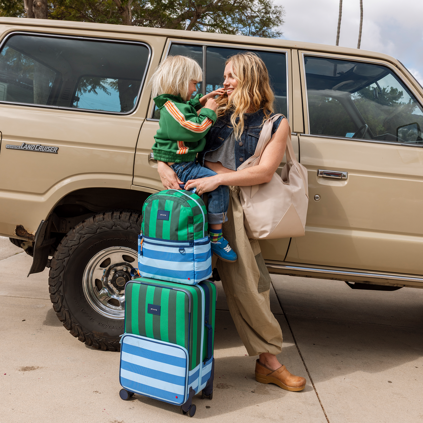 Woman and child with striped suitcases in front of a beige SUV