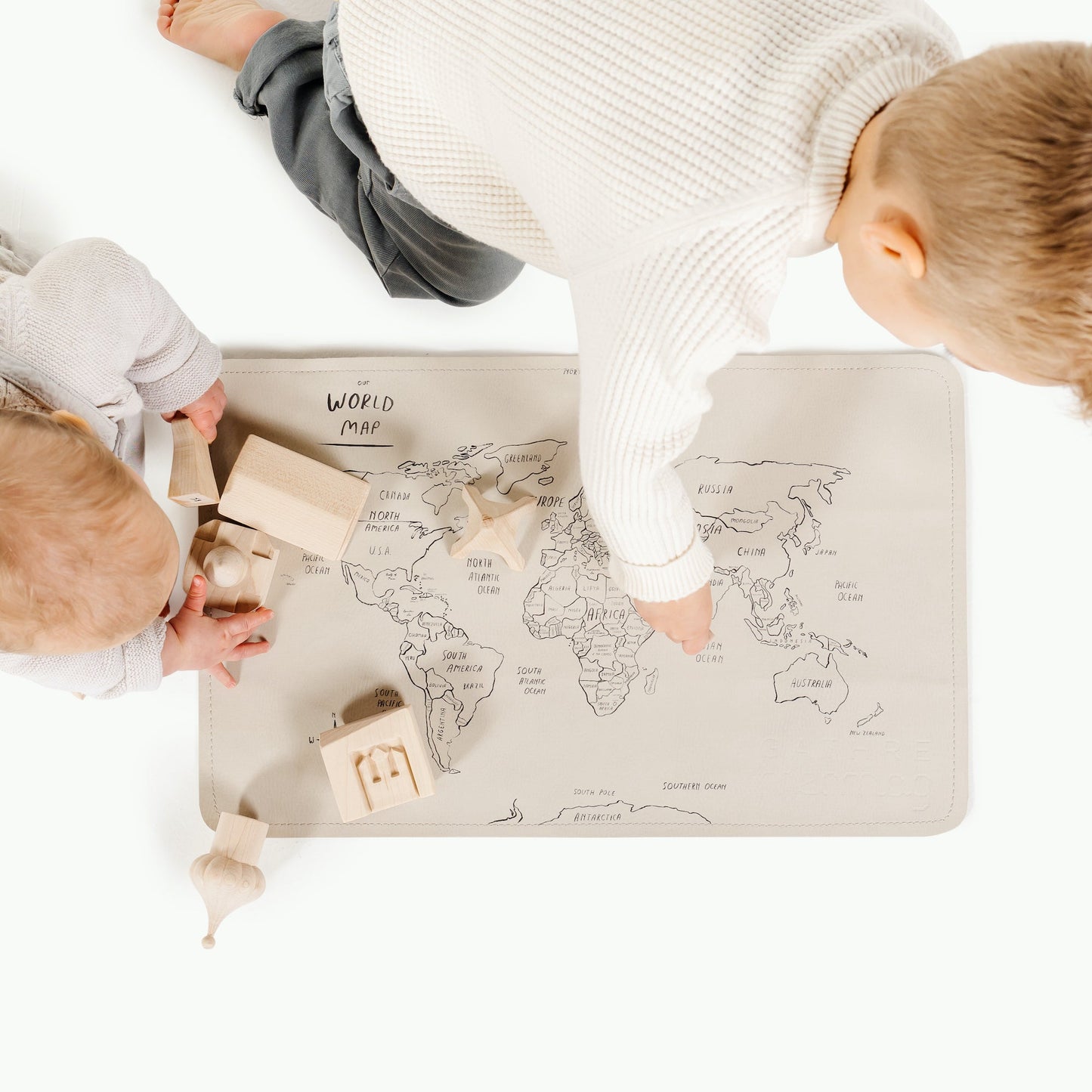 Two children playing with wooden toys on a world map mat.
