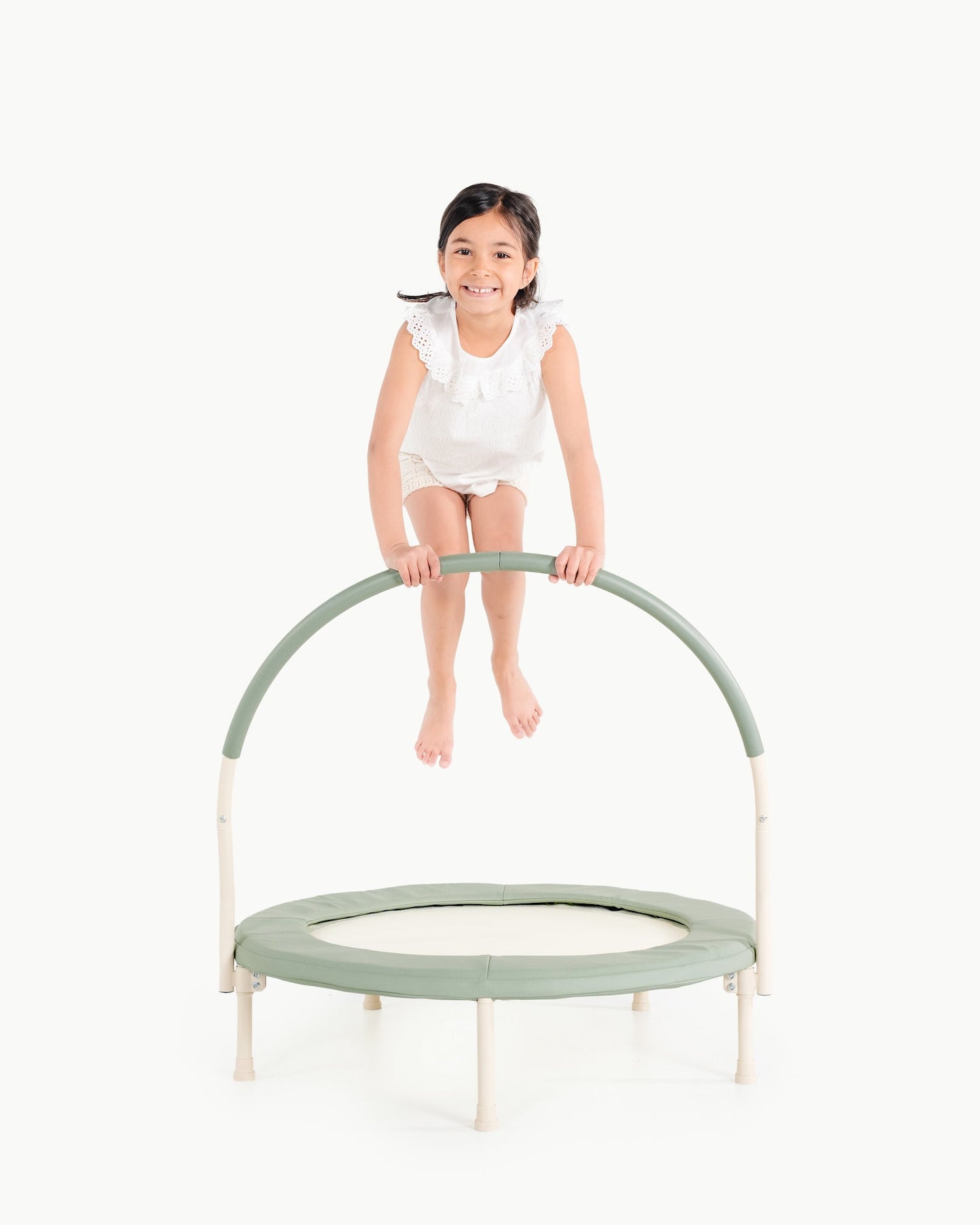 Child on a small green trampoline with a white background