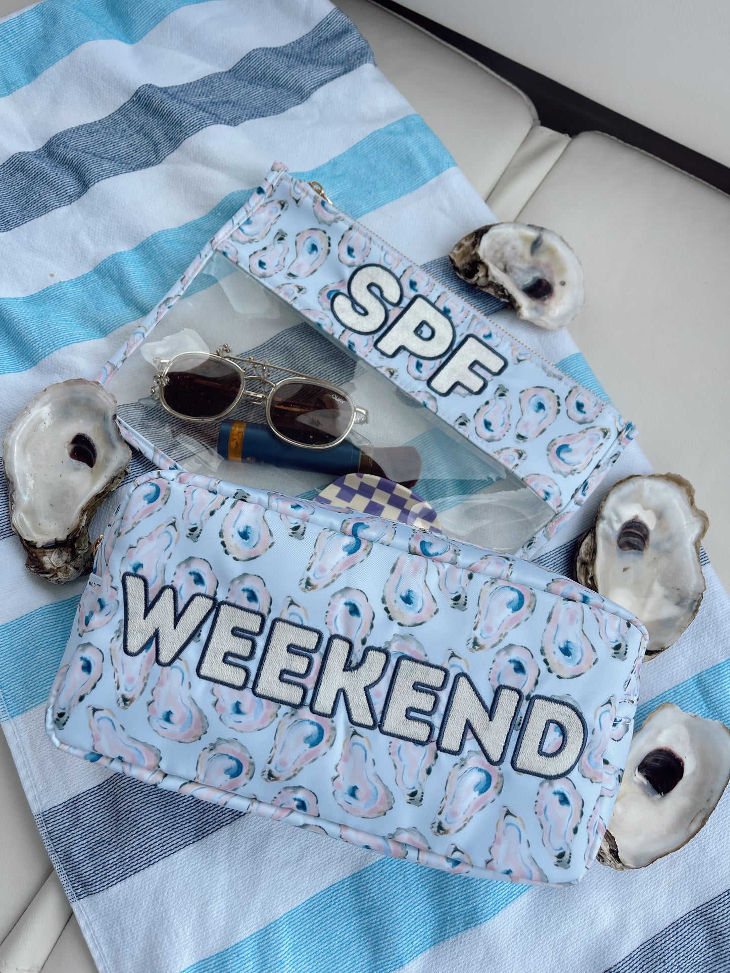 SPF and Weekend pouches with sunglasses on a striped fabric background