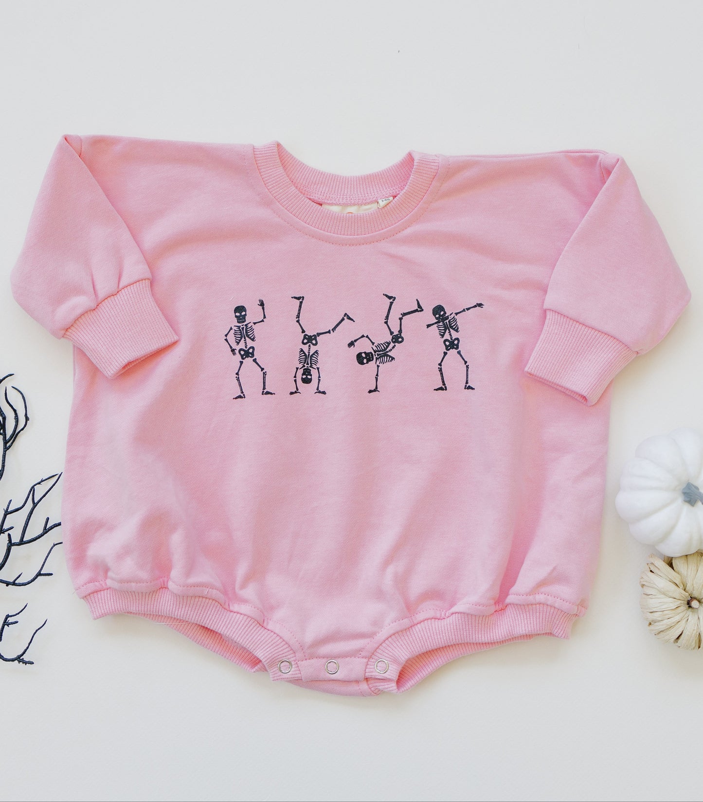 Pink baby romper with skeleton design on a white background
