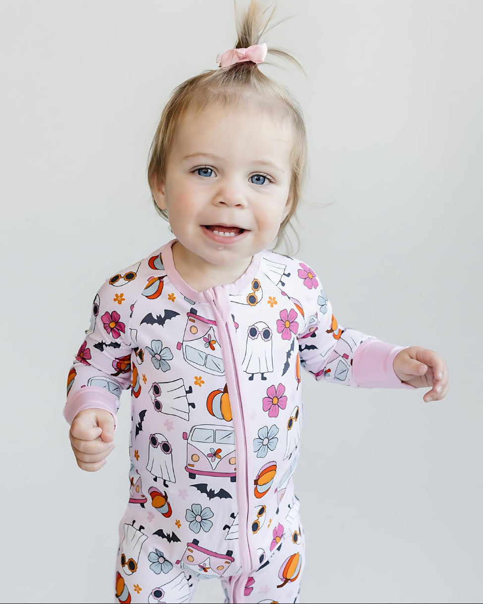 Child wearing a colorful onesie with cartoon designs on a plain background