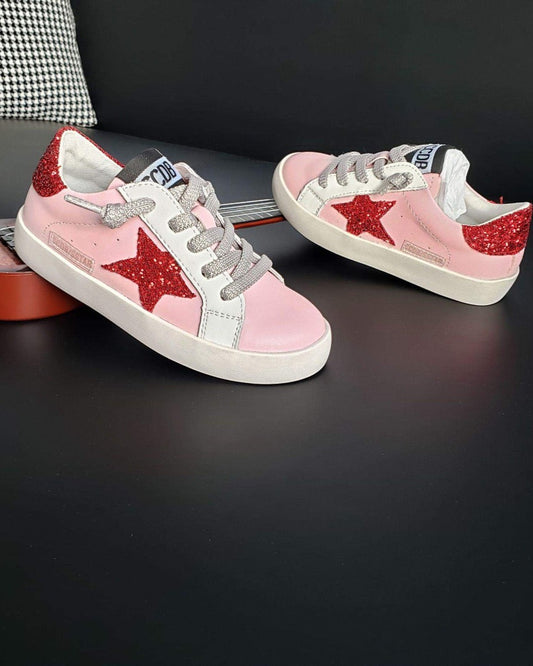 Pink sneakers with red stars on a dark surface