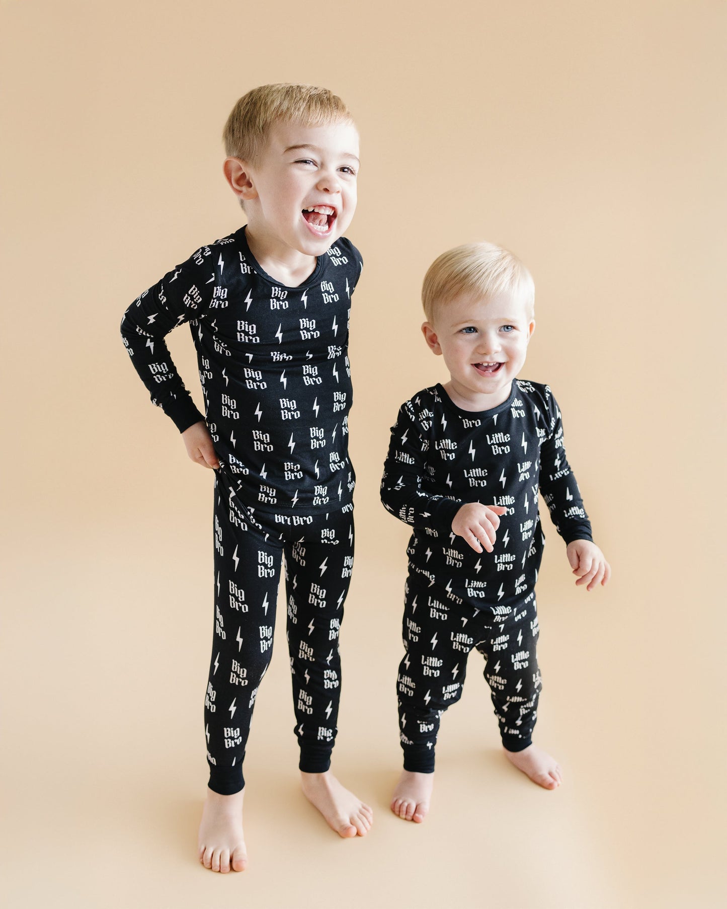 Two children wearing black pajamas with white text and graphics on a beige background