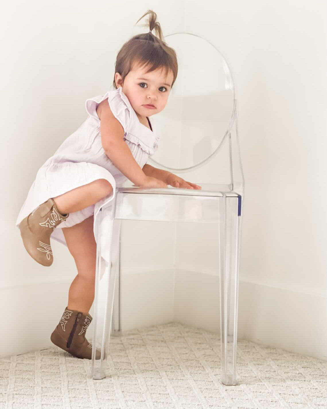 Child sitting on a transparent chair against a white background