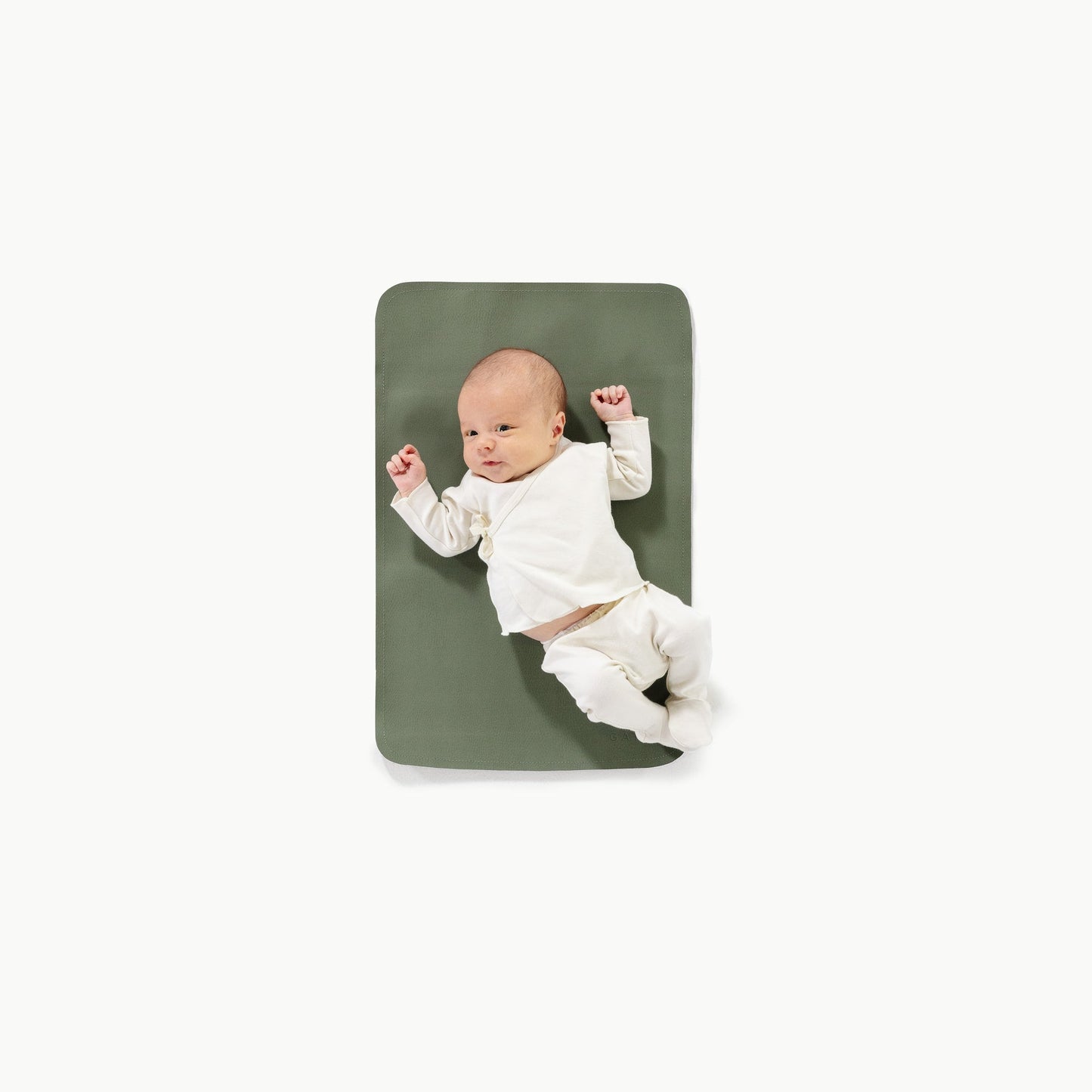 Baby lying on a green mat against a white background