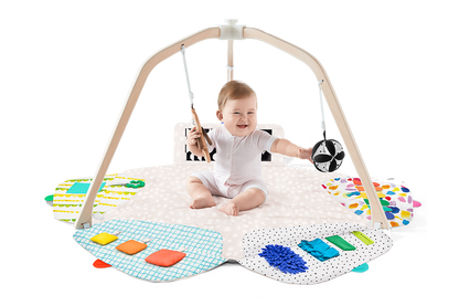 Baby playing with a colorful play gym on a white background
