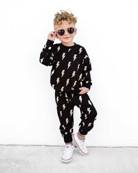 Child wearing a black outfit with lightning bolt patterns on a white background