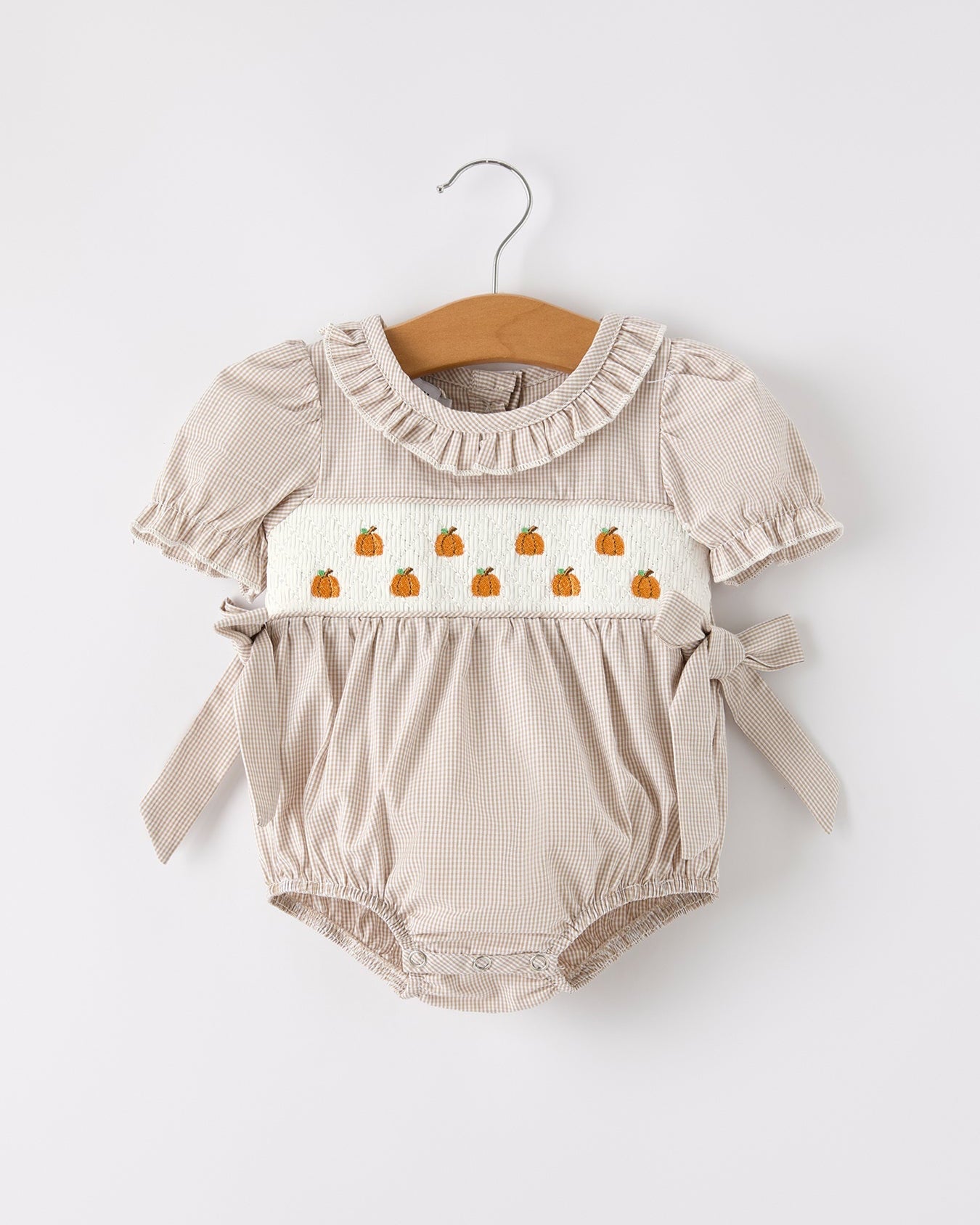 Beige baby romper with pumpkin design on a white background