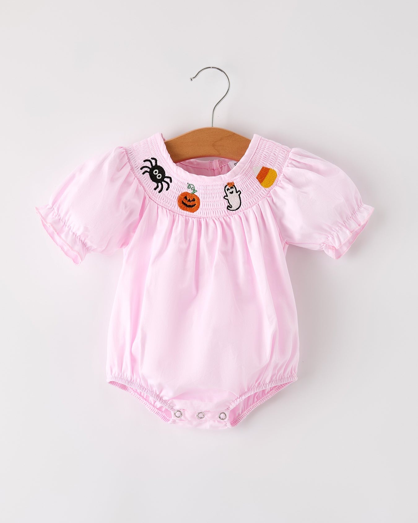 Pink baby romper with Halloween-themed embroidery on a white background