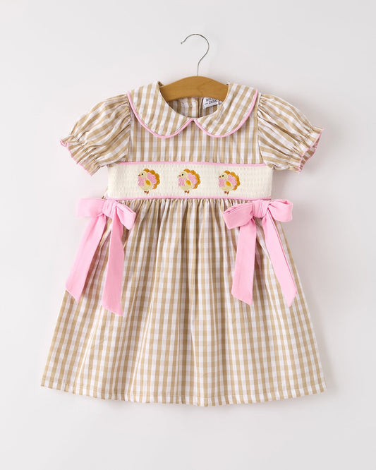 Children's dress with checkered pattern and pink accents on a white background