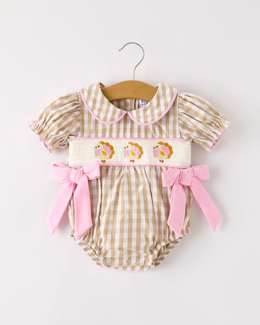 Baby romper with checkered pattern and pink accents on a white background