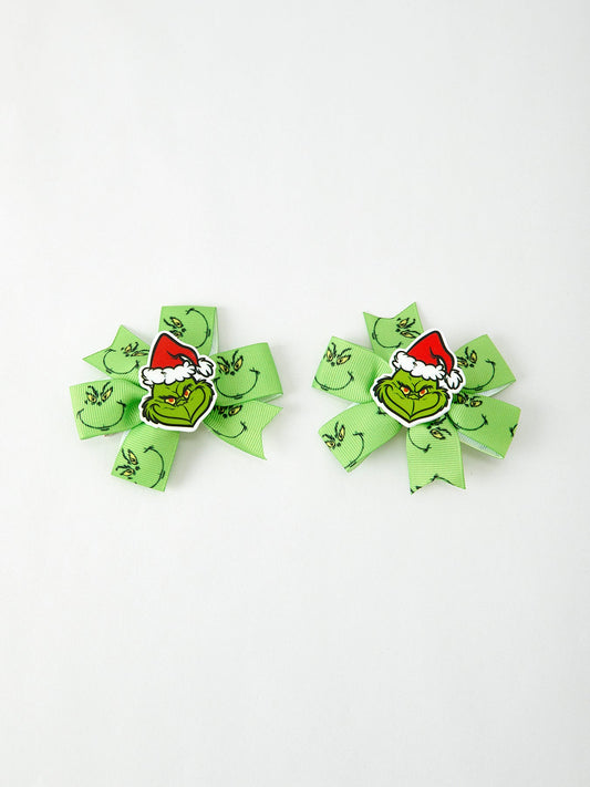 Two green hair bows with Grinch faces on a white background