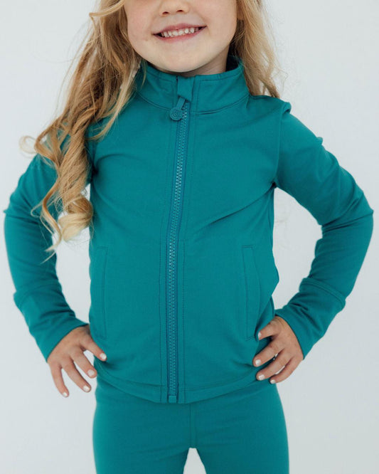 Child wearing a teal jacket and pants on a white background
