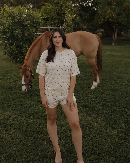 Woman standing next to a horse in a grassy field with trees in the background