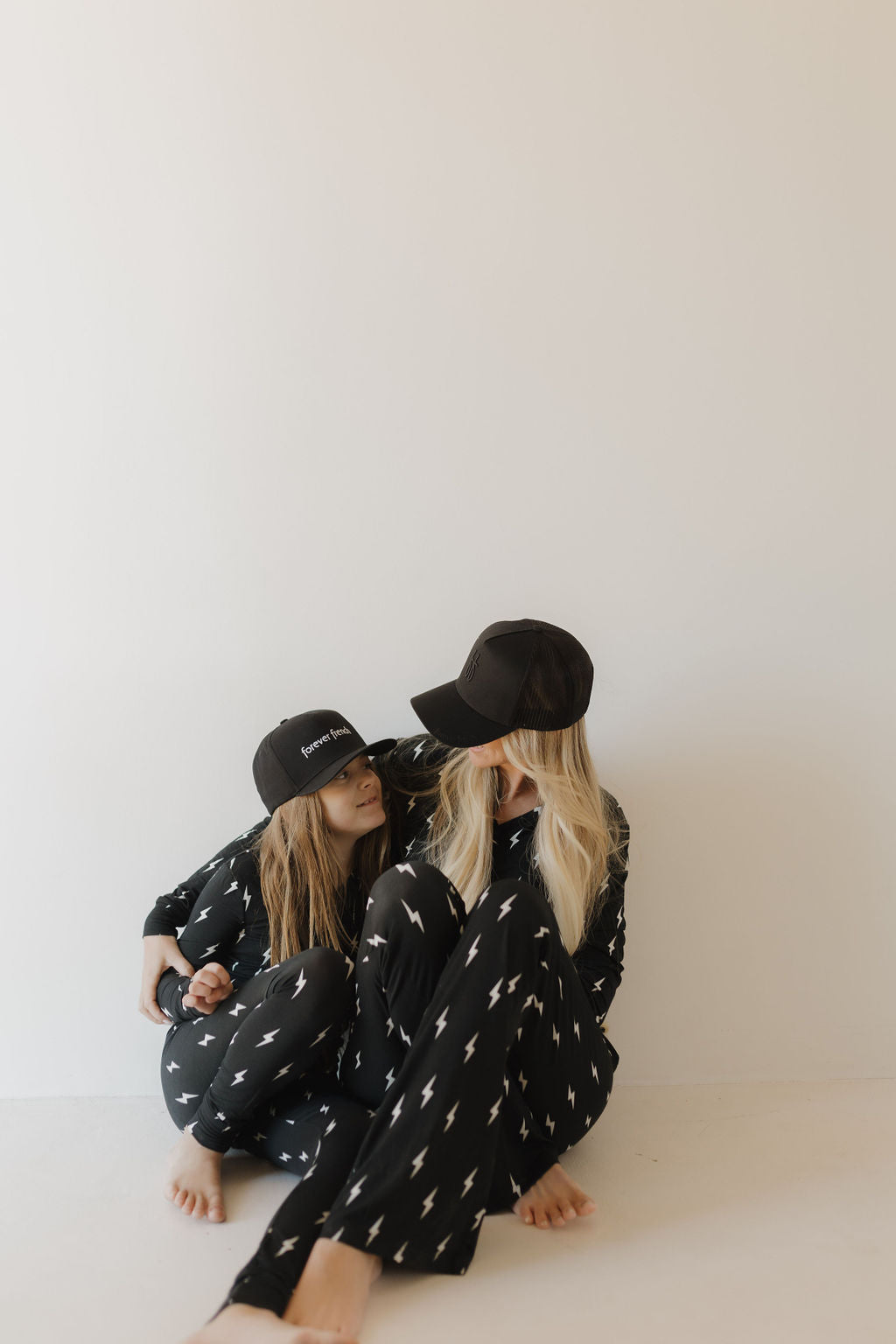 Two people sitting together wearing black hats and pajamas with star patterns on a white background