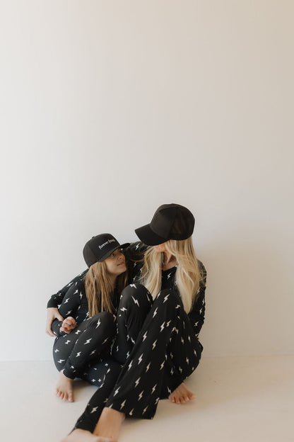 Two people sitting together wearing black hats and pajamas with star patterns on a white background