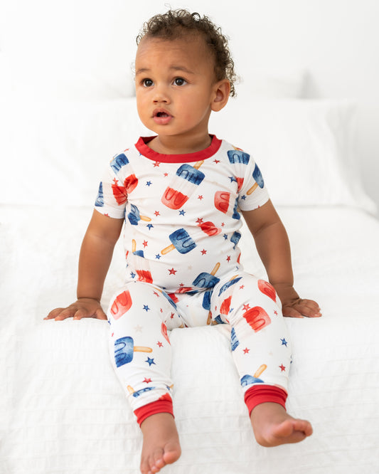 Baby wearing a colorful pajama set with ice cream and popsicle pattern on a white background