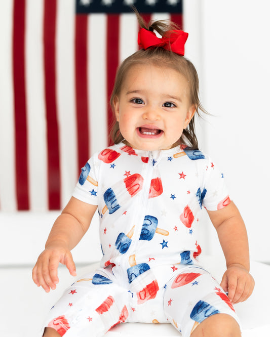 Child wearing a colorful outfit with ice cream pattern in front of an American flag