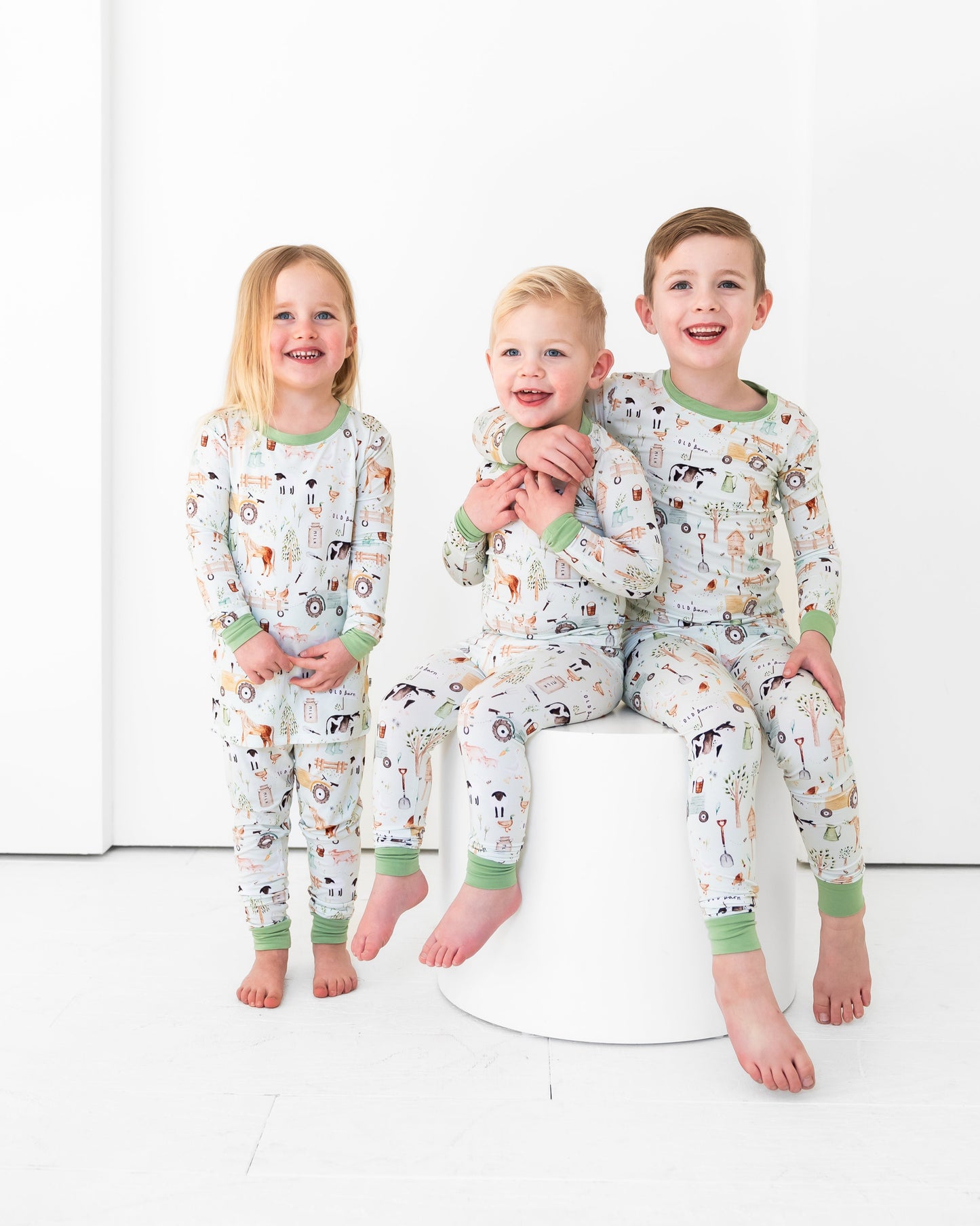 Three children wearing matching pajamas with animal prints on a white background