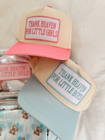 Two hats with text 'Thank Heaven for Little Girls' and 'Thank Heaven for Little Boys' on a neutral background.