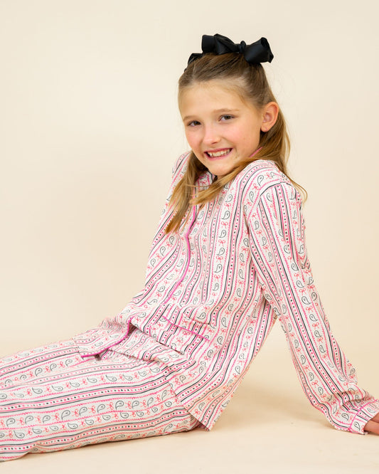 Young girl wearing a pink and white patterned pajama set on a beige background
