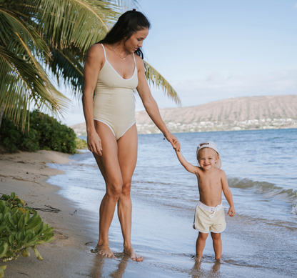 Woman and child holding hands on a beach with palm trees in the background