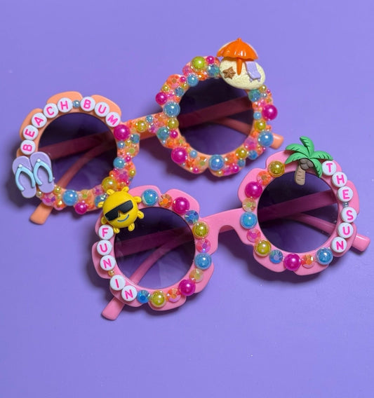 Colorful children's sunglasses with decorative elements on a purple background