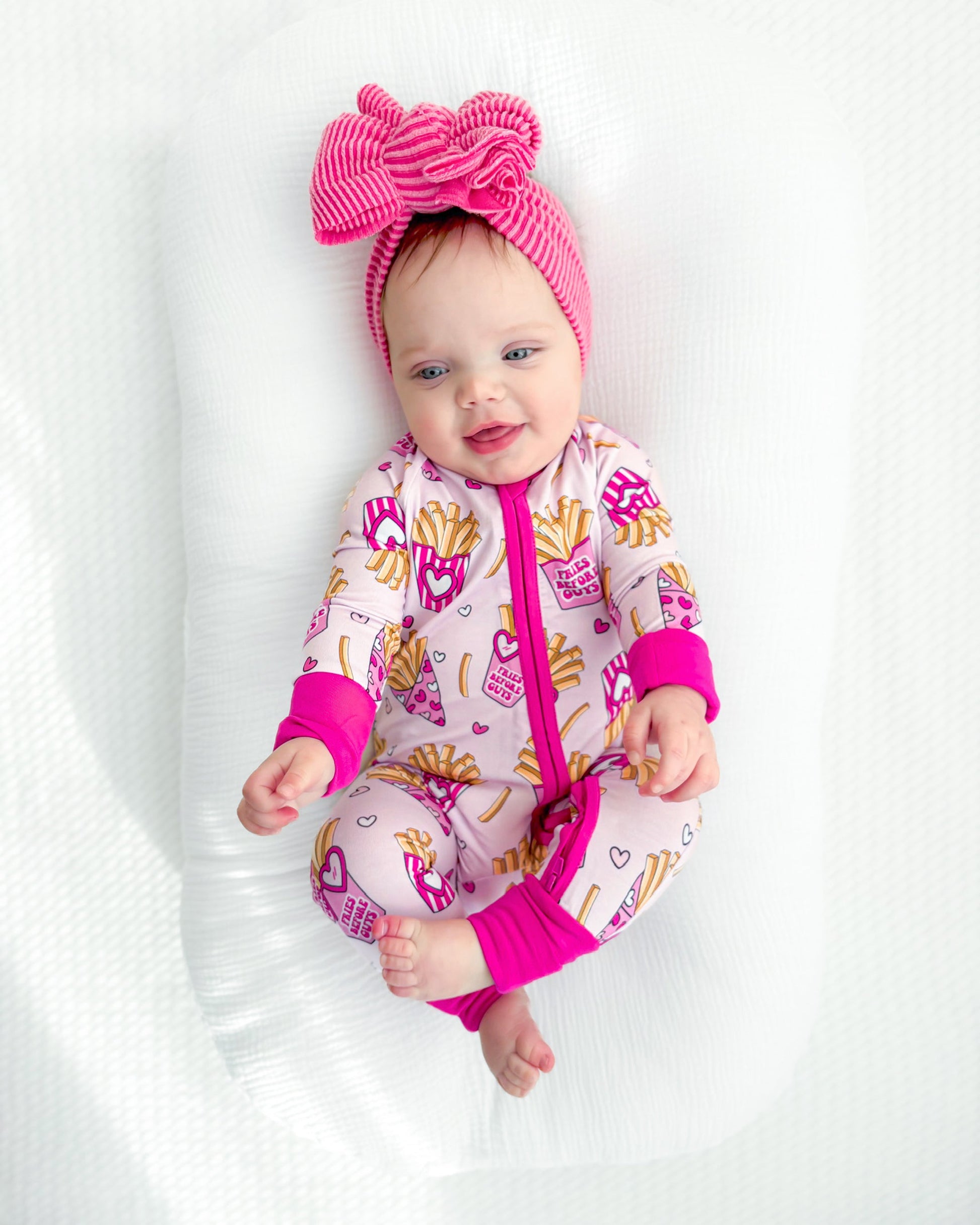 Baby in a pink and white outfit with a large bow on a white background