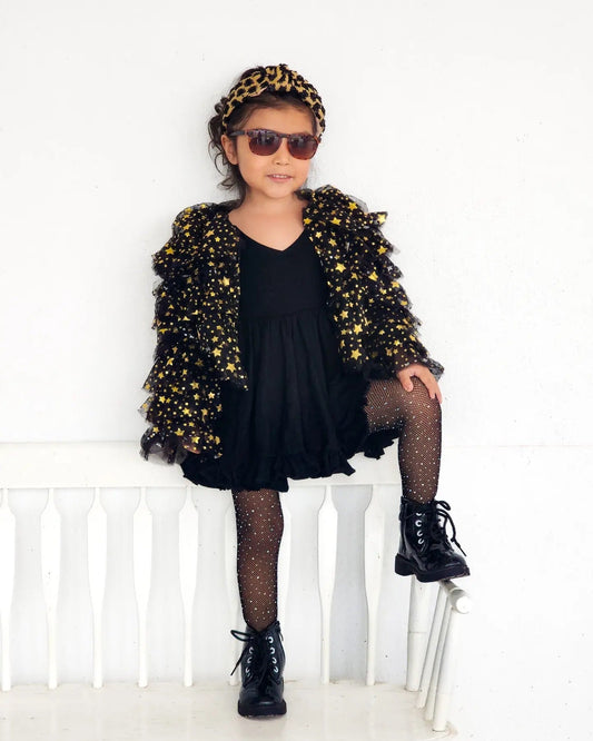 Person wearing a black dress, gold jacket, leopard print headband, and sunglasses on a white background