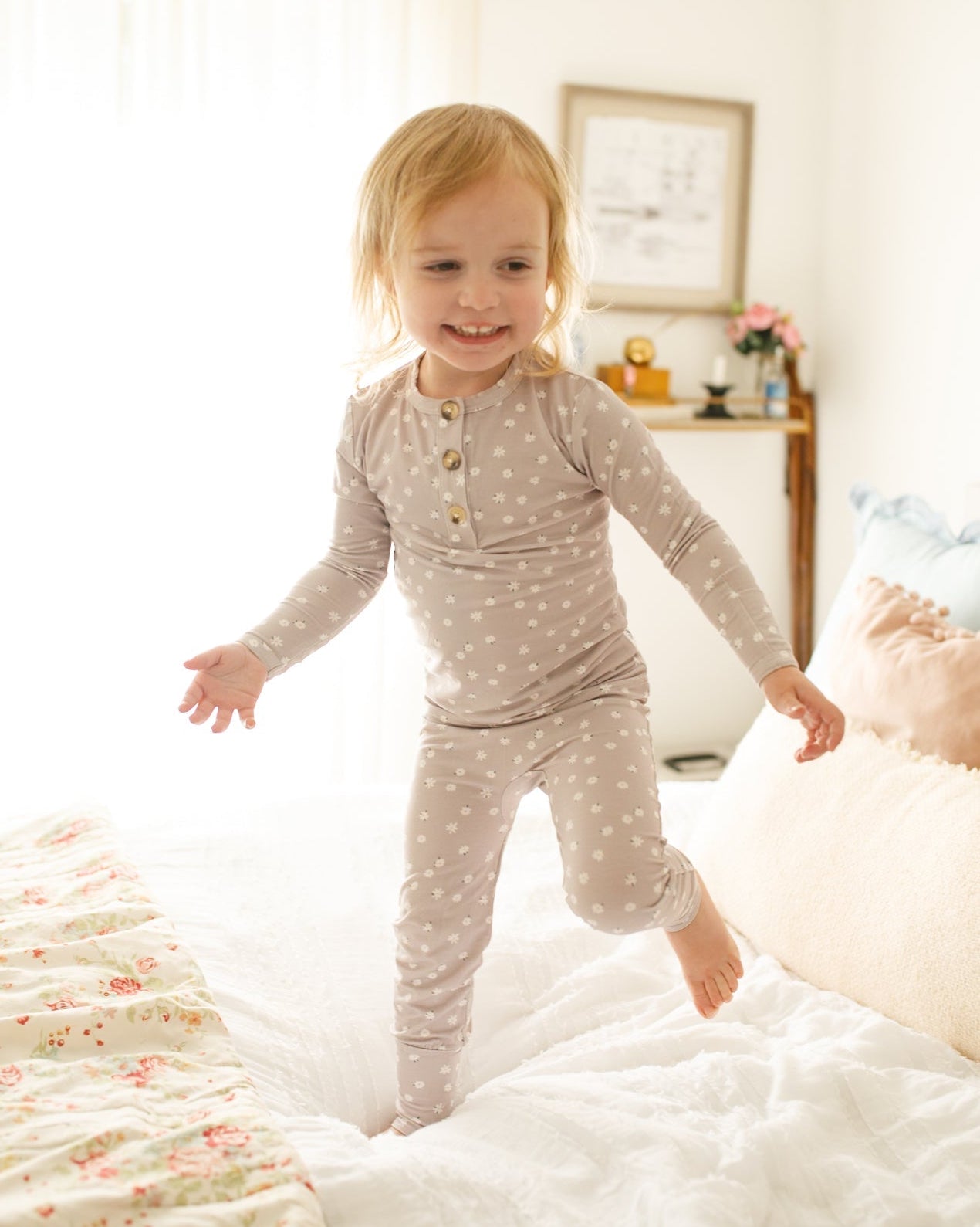 Child in pajamas jumping on a bed in a bedroom