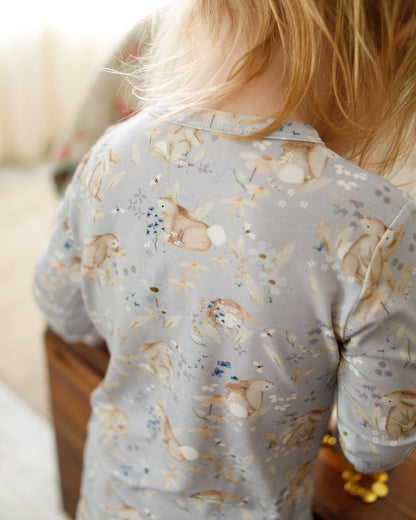 Child wearing a light blue long-sleeve shirt with bunny prints in a home setting