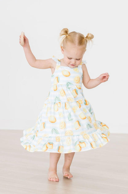 Young girl wearing a dress with lemon pattern on a plain background