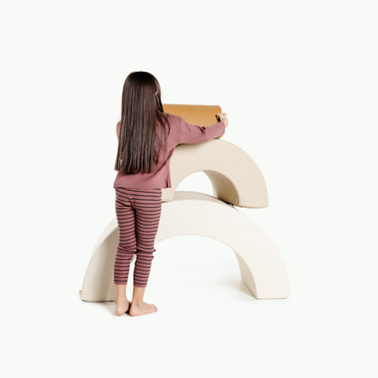 Child sitting on a white curved chair holding a cardboard box against a white background