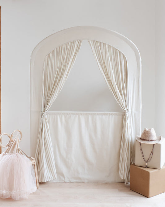 White curtain archway in a room with a window and decorative items.