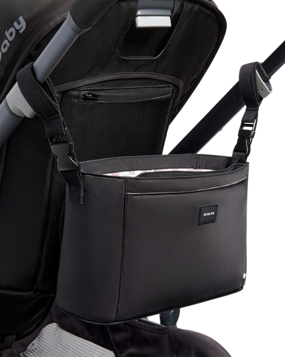 Black stroller organizer attached to a stroller on a white background