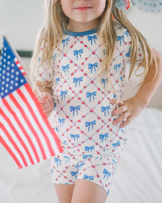 Child wearing a pajama set with red, white, and blue pattern, holding an American flag.