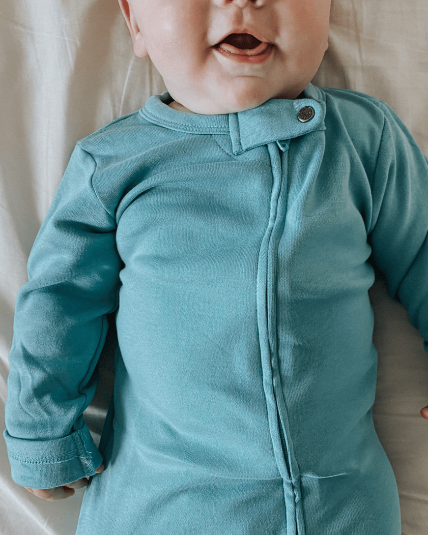 Baby wearing a teal onesie against a neutral background